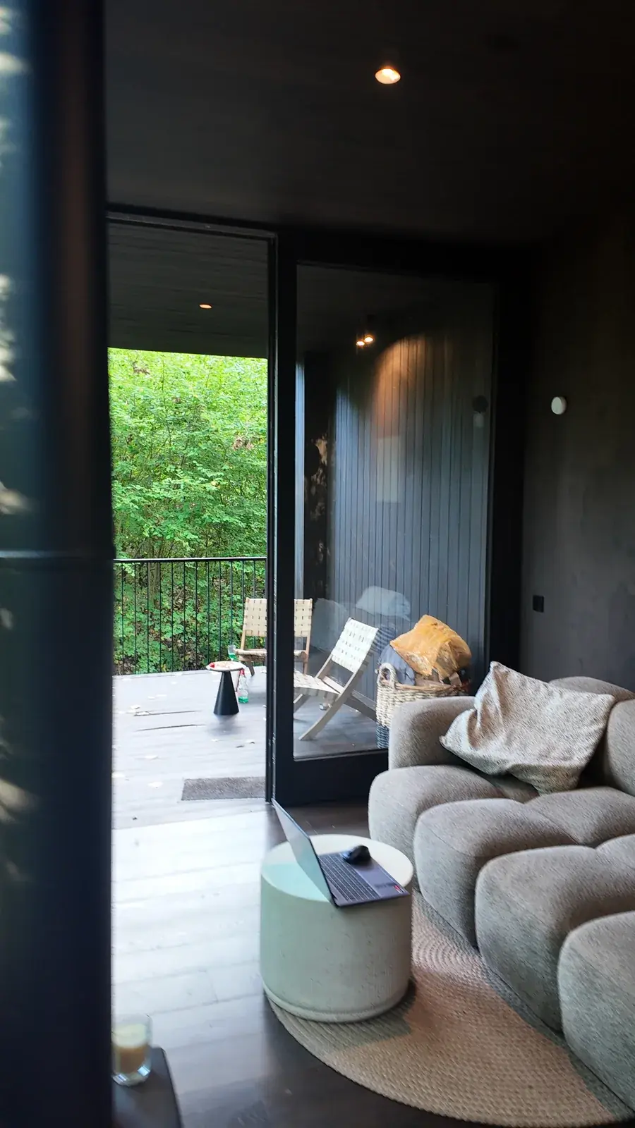 Le salon de la maison miroir ouvert sur la terrasse et la forêt